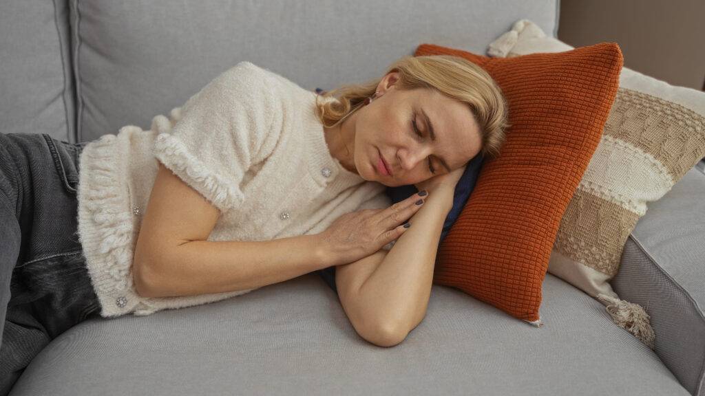 Nainen nukkuu uupuneena sohvalla