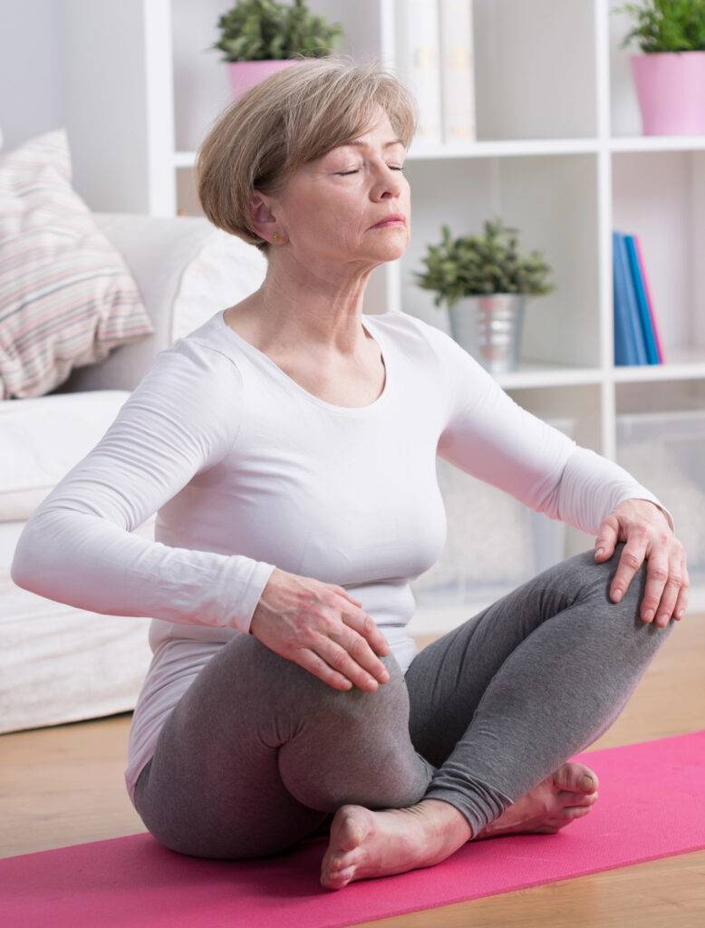 Säännöllinen tietoisuustaitojen harjoittaminen vähentää huoliajattelua ja parantaa unen laatua. Nainen rentoutuu ja meditoi.