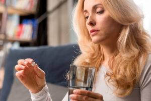 Tamoksifeenihoito rintasyövän jälkeen. Mietteliäs nainen ottaa lääkkeen.