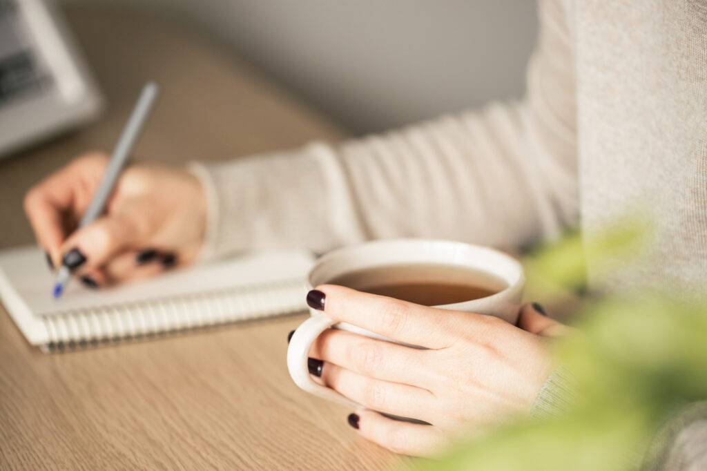 Huolipäiväkirjan pitämisen on todettu vähentävän nukahtamisviivettä vähentämällä yöllistä murehtimista. Nainen kirjoittaa huolipäiväkirjaa ja juo iltateetä.